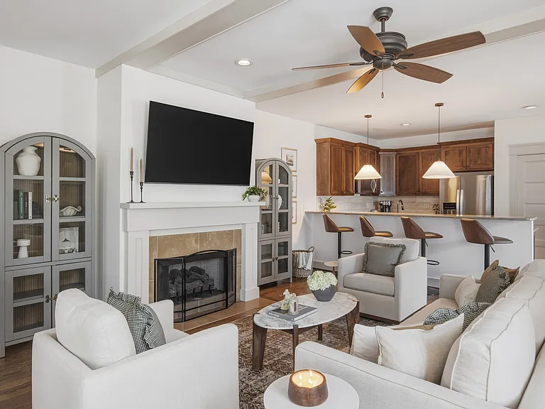 Beautifully designed living room with a fireplace, ceiling fan and plenty of comfy seating. Smart TV, wood floors, and easy flow into the kitchen.