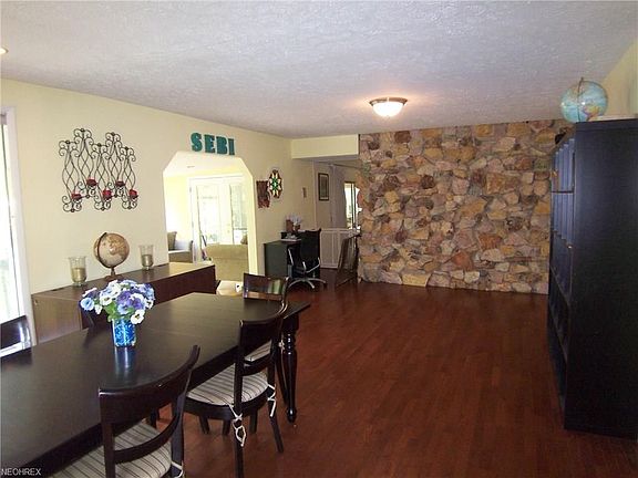 The dining room features the stone back wall of the livingroom fireplace. Notice entry to the one of two sunrooms on the left.