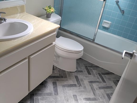 Sink, new water proof vinyl flooring overhead shower and tub, new glass sliding doors.