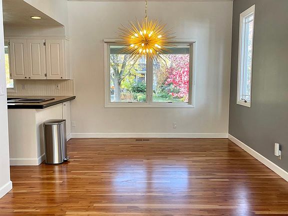 Dining room and entrance to kitchen with beautiful hardwood floors and new front facing Pella windows with Hunter Douglas blinds