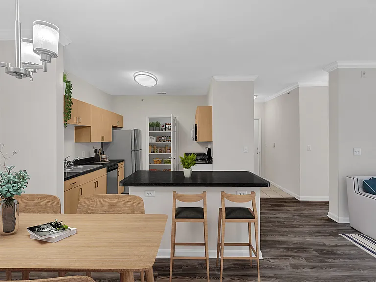 A kitchen with a black countertop and wooden chairs.