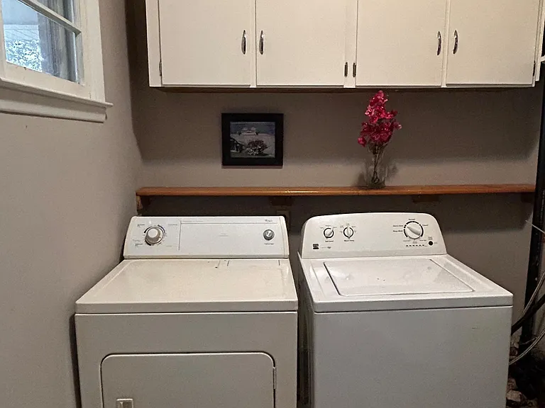 Dedicated laundry area with full-size washer and dryer plus overhead cabinets and a convenient folding shelf.