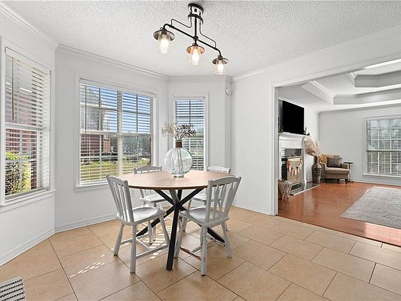 Dining area featuring crown molding, a fireplace, light tile patterned flooring, a textured ceiling, and a tray ceiling