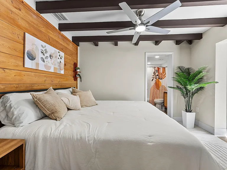 Spacious bedroom with a wood accent wall, ceiling fan, and direct access to an adjacent bath for added convenience.