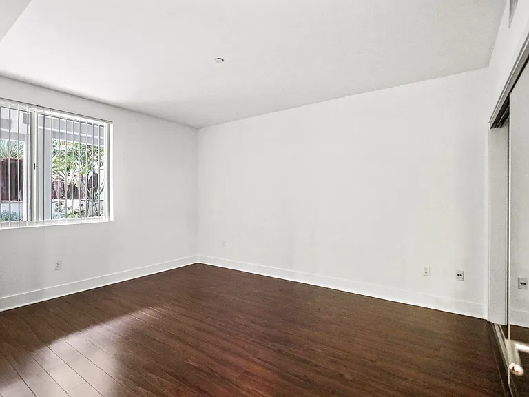 Bedroom with a Mirrored Closet, Vinyl Flooring, and Large Window