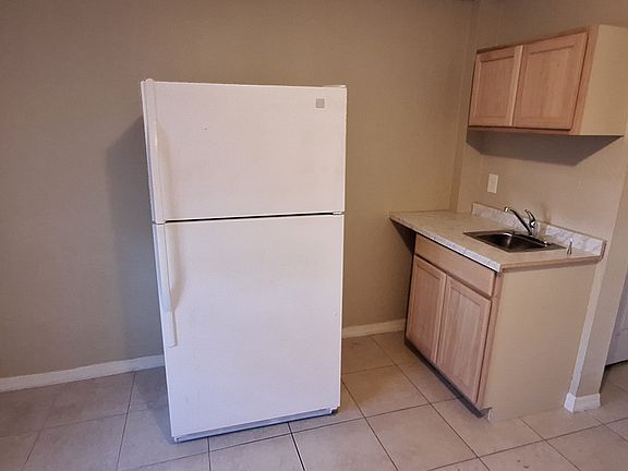 Kitchenette with refrigerator, sink, 2 burner countertop stove, and storage.