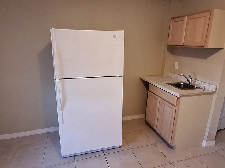 Kitchenette with refrigerator, sink, 2 burner countertop stove, and storage.