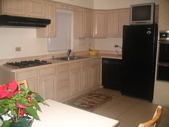 Neutral kitchen has light wood cabinets and new black appliances