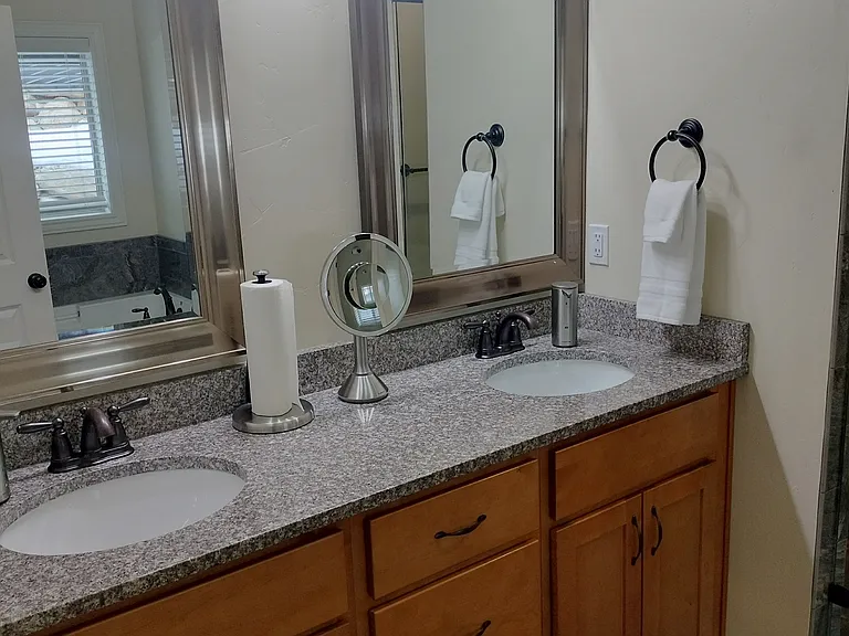 Spacious master bathroom with double sinks, a glass shower, and a large deep tub_perfect for relaxing after a long day. Designed for comfort and style, this serene retreat offers the ultimate in convenience and luxury.
