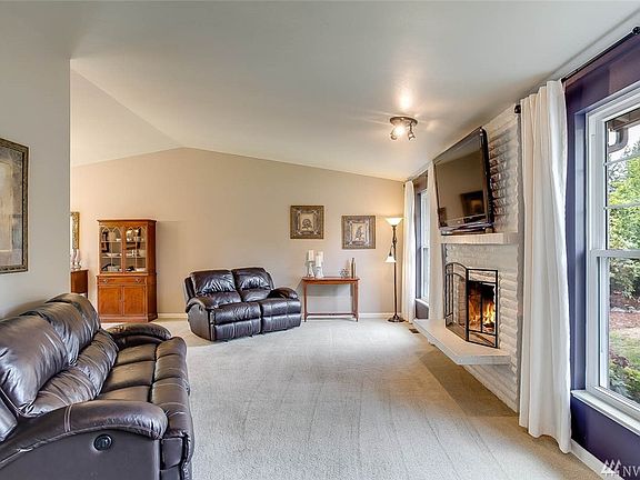 Inviting entrance leads you to a formal living room featuring dramatic vaulted ceilings, a cozy wood burning fireplace and amazing natural lighting, drenching the room in sunlight.