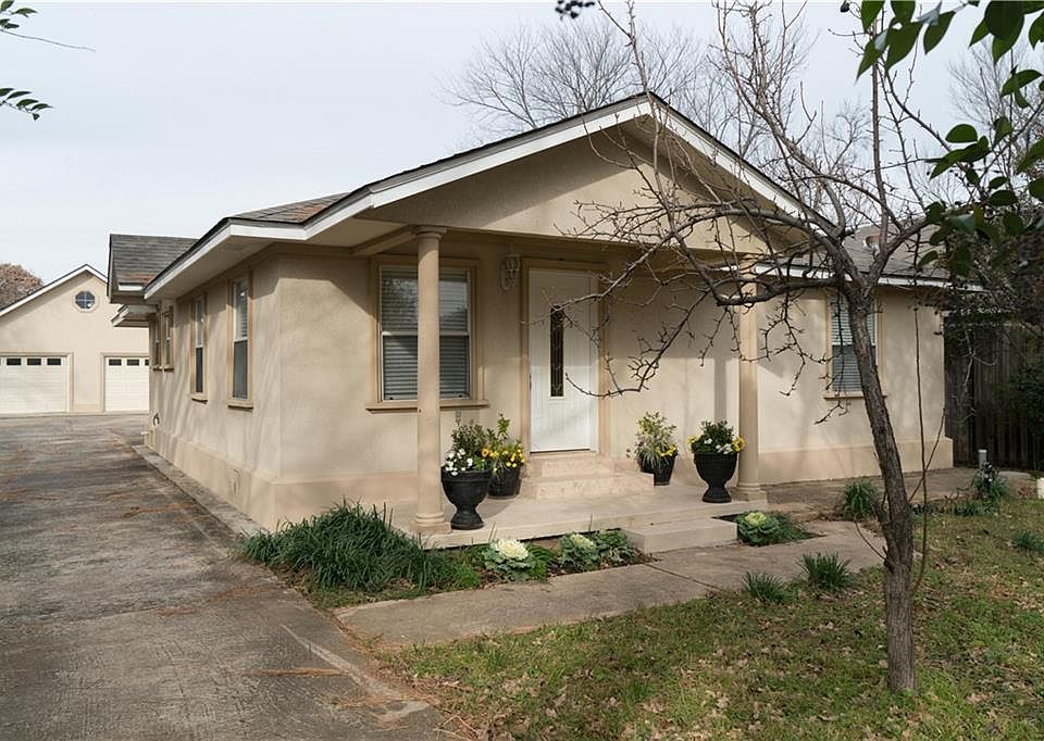 Front of home with covered porch and long driveway leading to detached garage