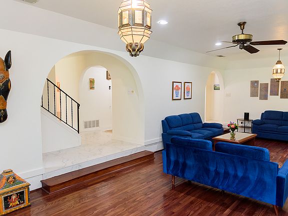 Open and inviting living room featuring a cozy couch, two love seats, a ceiling fan for comfort, and elegant dual archway entrances that add character and flow.
