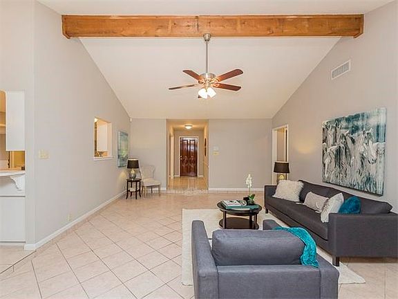 Living room open to kitchen, with high vaulted ceiling.