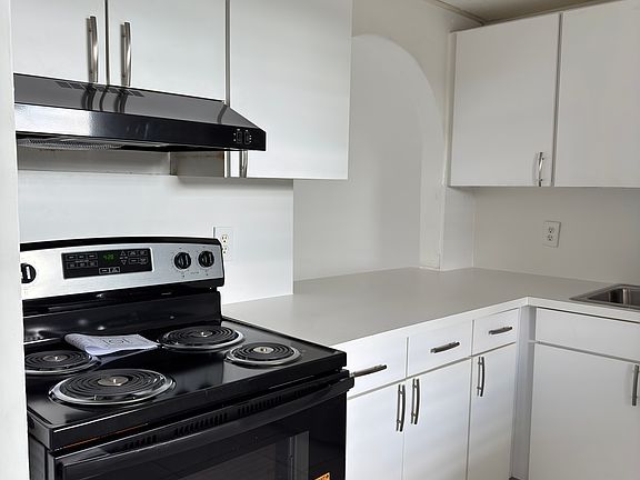 Full kitchen with all new appliances and countertops. An arch overlooking the living room with seating.