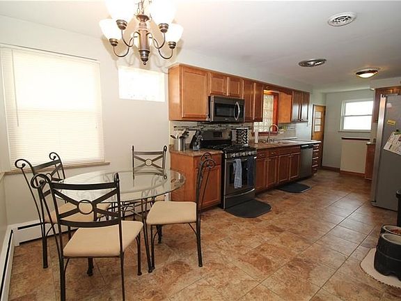 Spacious eat-in kitchen includes stainless steel gas stove, microwave, dishwasher, and refrigerator.