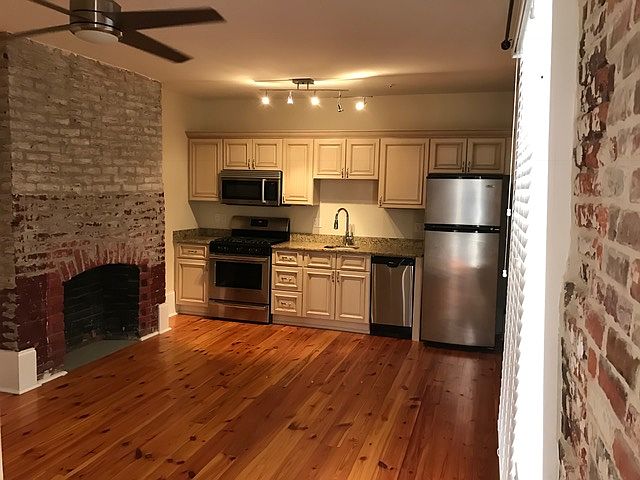 Open concept - living / dining / kitchen. Exposed brick walls and furnished stainless appliances