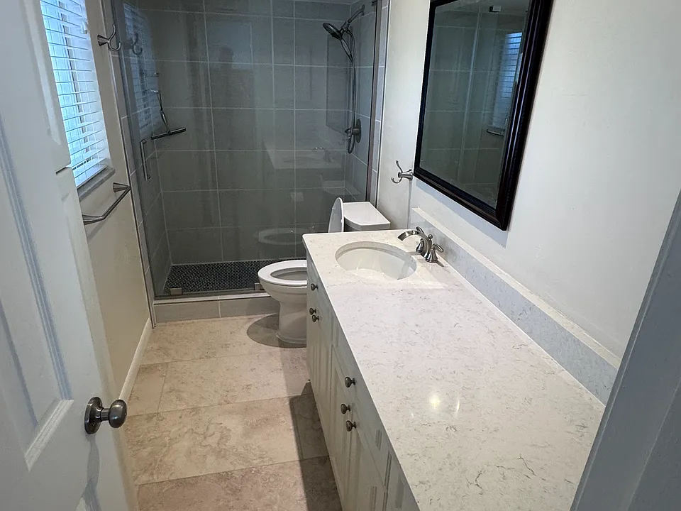 Master bathroom, newly renovated with quartz countertop, new luxury vinyl flooring (same as Guest Bathroom and Kitchen flooring), tall toilet, new sink and hardware, and new tiled shower with sliding glass door (frameless) and new shower fixtures.
