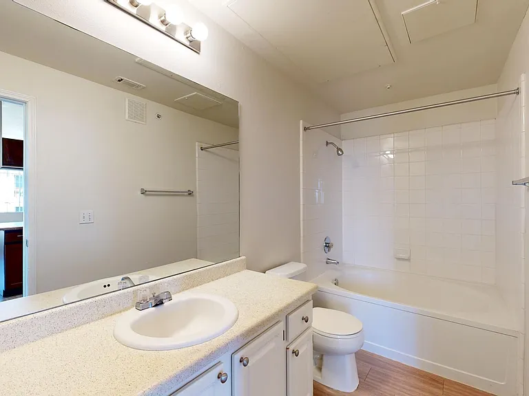 Apartment bathroom with large soaking tub and wood-style flooring.