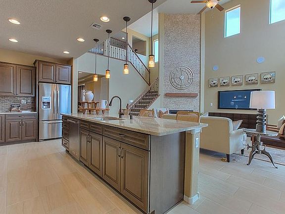 Kitchen overlooks gathering room with large two-story ceilings for the ultimate bright and open feel