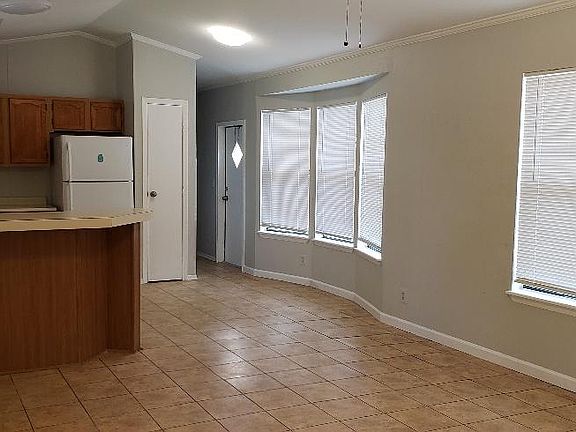 Open concept view of kitchen/dining areas from living room. Kitchen pantry and back door visible.