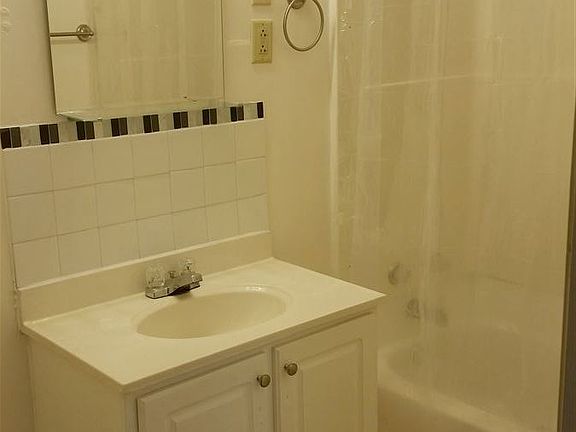 Tub with shower in bathroom, plus linen closet.