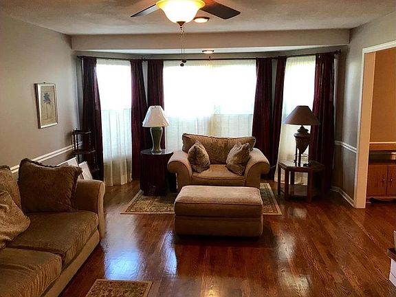 Living room with ceiling fan, bay window and custom blinds.