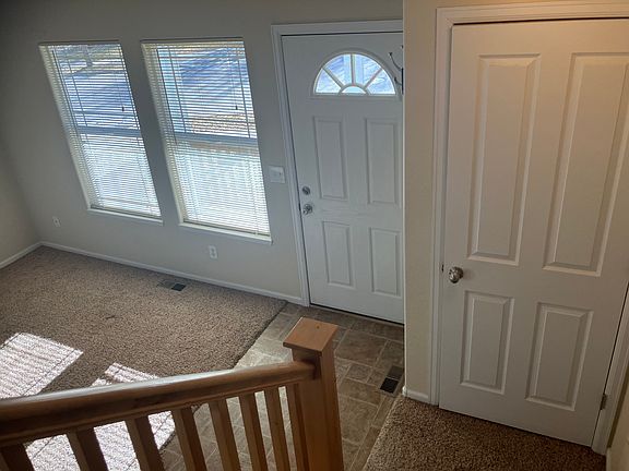 View Coming Down the Stairs to the Coat Closet, Living Room and Front Door Entry