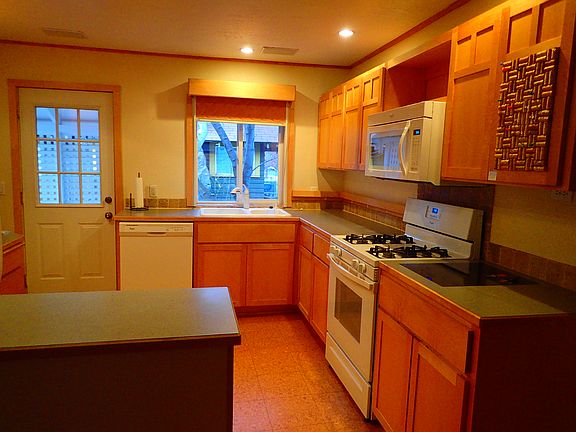 Kitchen, showing custom cabinets, stove/oven, microwave, dishwasher, back door to backyard