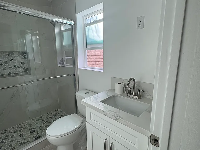 Primary bath attached to primary bedroom with beautiful shower doors and inside shelf