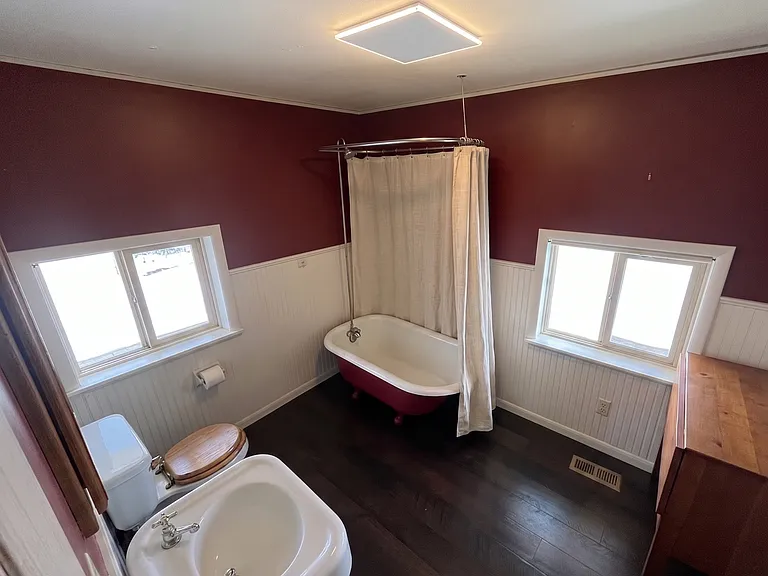 Private en-suite bath attached to the main floor bedroom, complete with a clawfoot tub and shower setup.