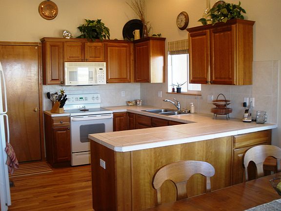 Kitchen has maple cabinets, tile countertops