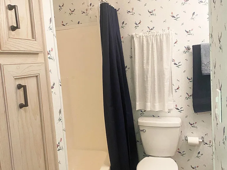 Bathroom has a tub and shower plus pantry space for linens
