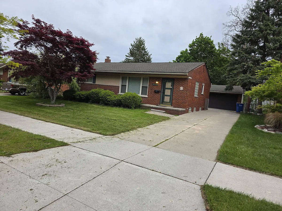 Brick ranch home with driveway, detached garage, front porch entry, and a spacious yard with mature landscaping. - 31340 Pagels Dr