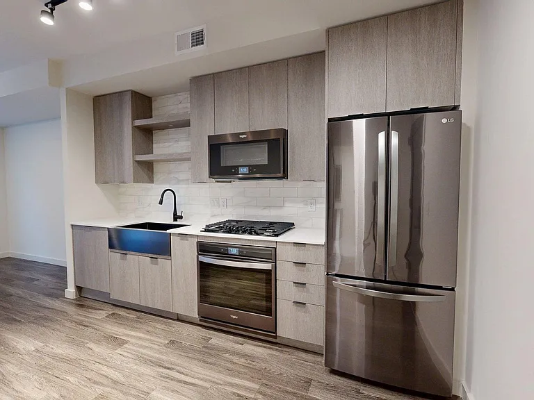 Apartment Kitchen with Stainless Steel Appliances, Quartz counter tops and Wood Style Flooring.