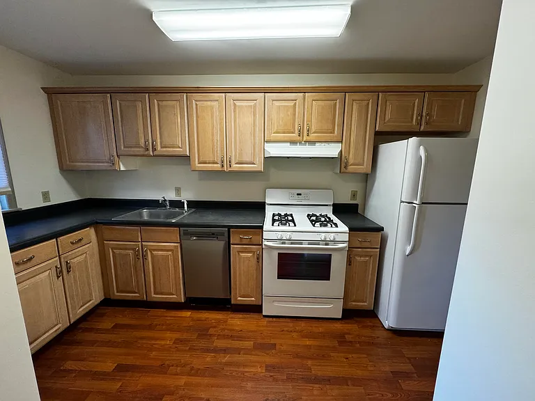 Kitchen area equipped with dishwasher, refrigerator, stove/oven. Gleaming hardwood floors.