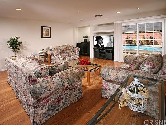 The living room is bathed in natural light accenting its complementary contemporary wood flooring, smooth ceiling with recessed lighting, a built-in media alcove, plus its elegant sliding glass door provides direct access to the spectacular backyard.