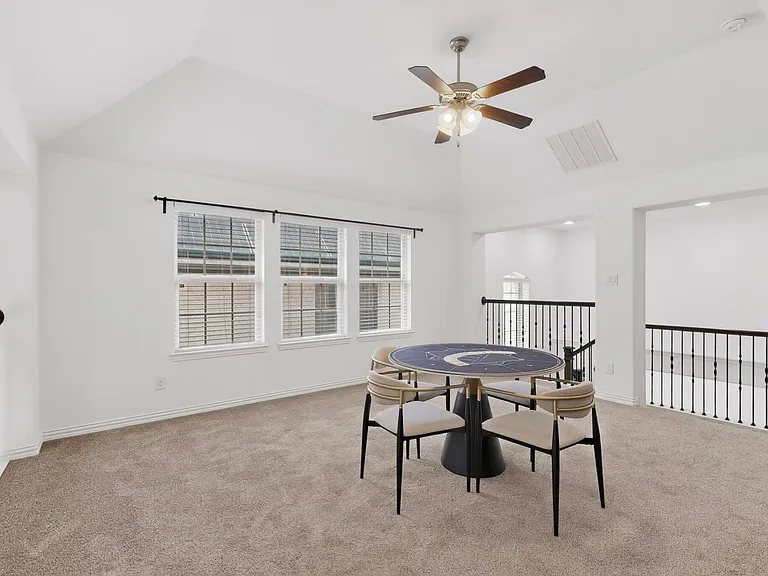 A spacious den featuring wide windows and a ceiling fan, creating a comfortable space.