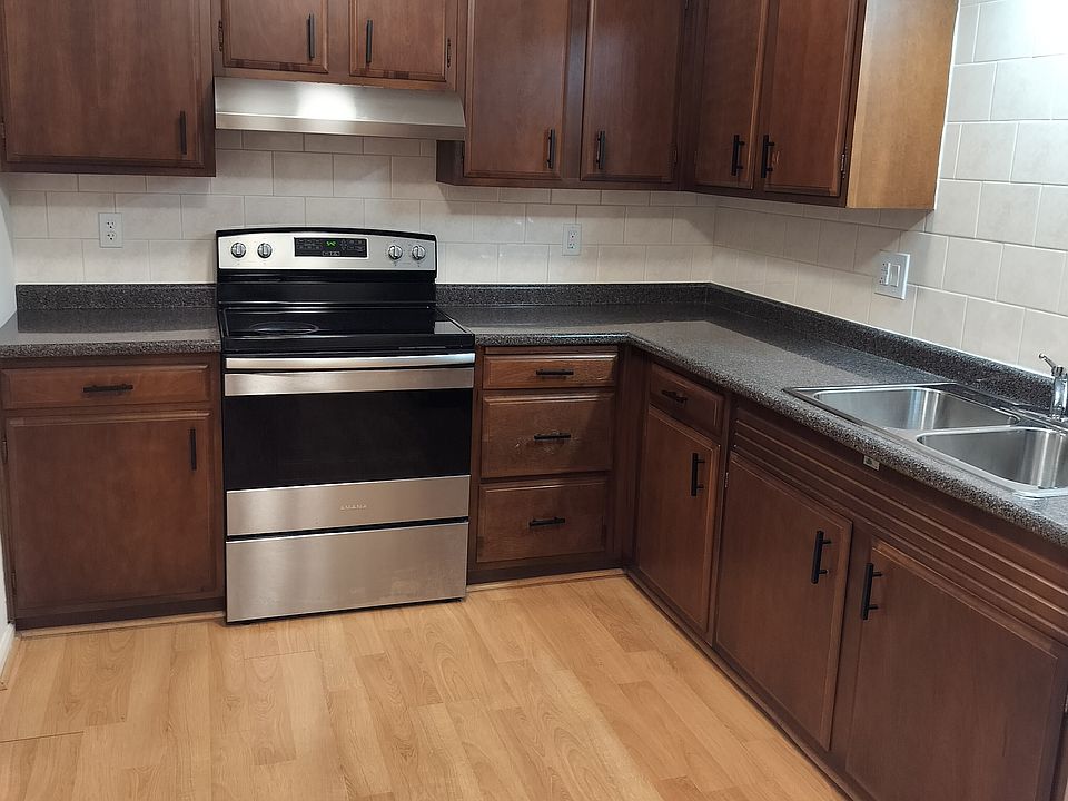 Ceramic tile surrounds countertop and cabinets. Hood vents out. Newer appliances and also a garbage disposal.
