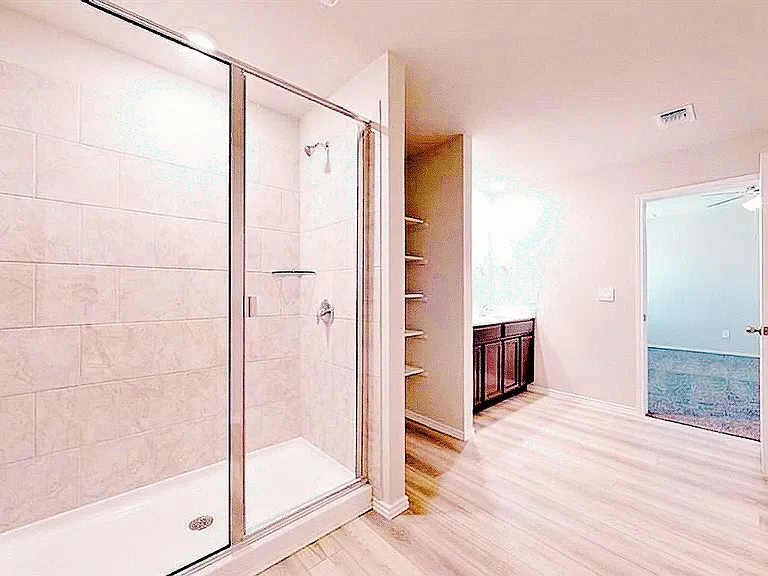 Primary bathroom with dual-vanity sinks, a walk-in shower, built-in linen shelving, and a spacious walk-in closet."