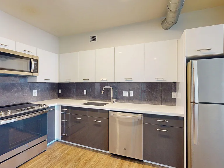 Apartment Kitchen with Quartz counter tops and Wood-Style Flooring.