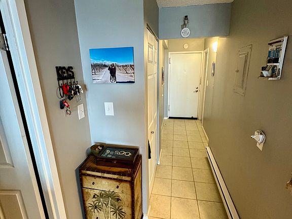 Standing at edge of living room, looking back at front door, half bathroom door to the right, and bedroom side of condo door on the left.