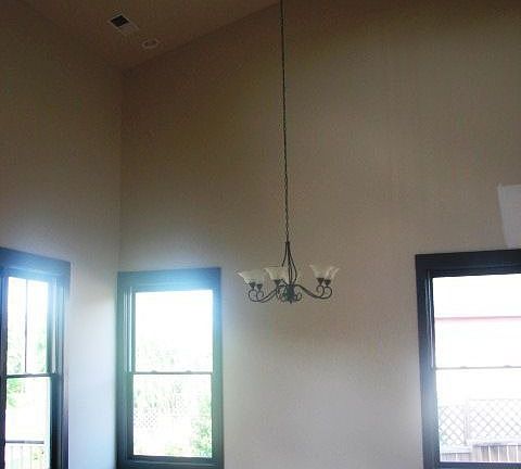 Large 2 story dining room with chandalier, many windows, hardwood floors open to kitchen.