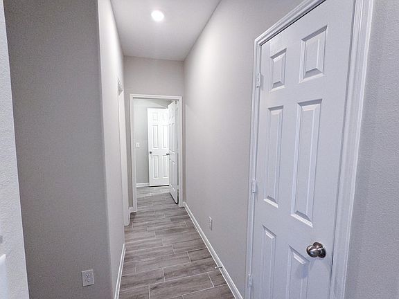 Hallway to half-bath and laundry room. Coat closet on the right hand side