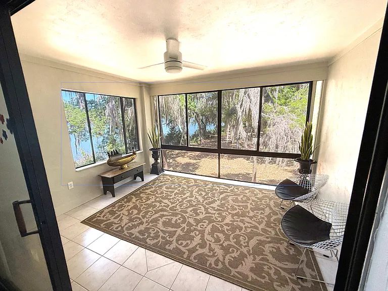 Sunroom featuring tree canopy & lake views