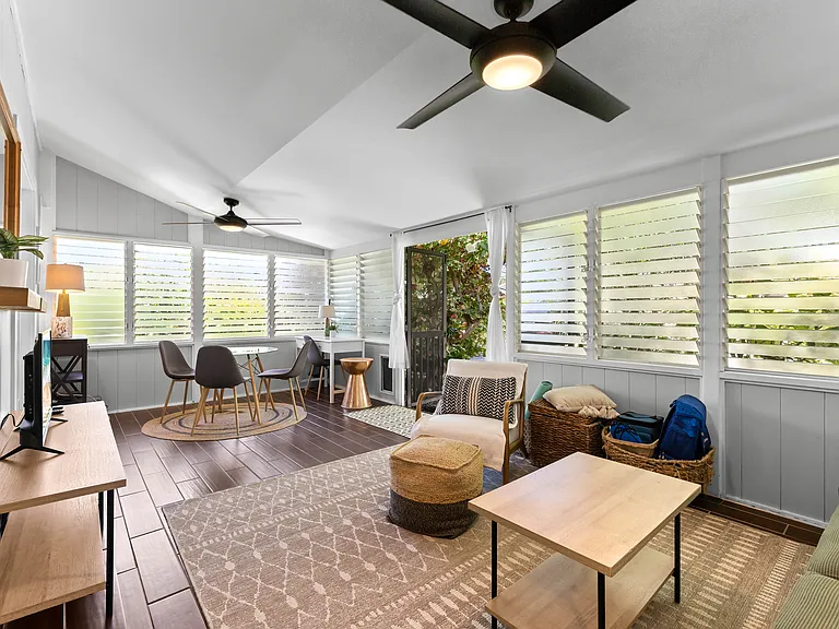 Enclosed lanai adds additional living space, a futon sofa, chair, TV, small dining set for 3-4, and a desk. Two large fans and lots of windows keep this area cool.