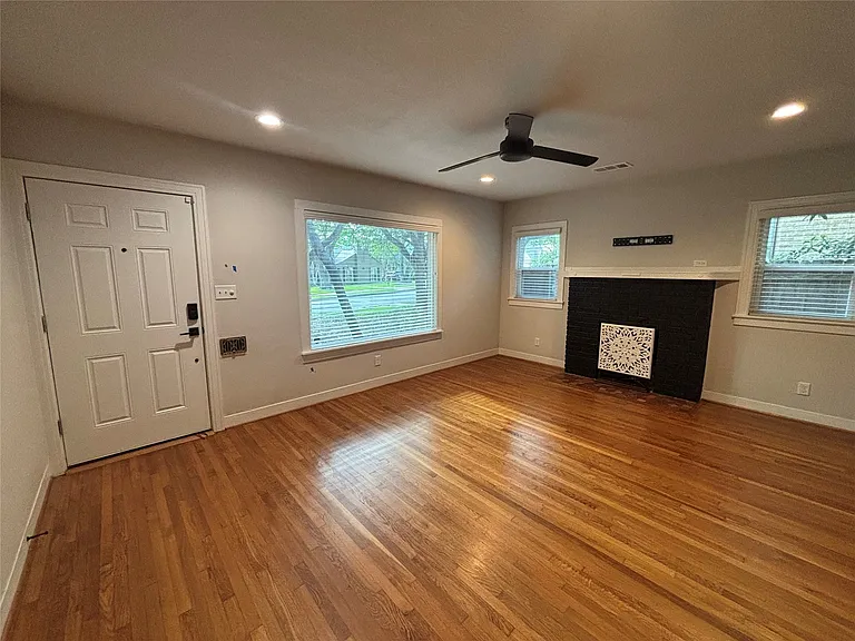 Hardwood flooring featured throughout this living area, complemented by a modern ceiling fan with integrated lighting