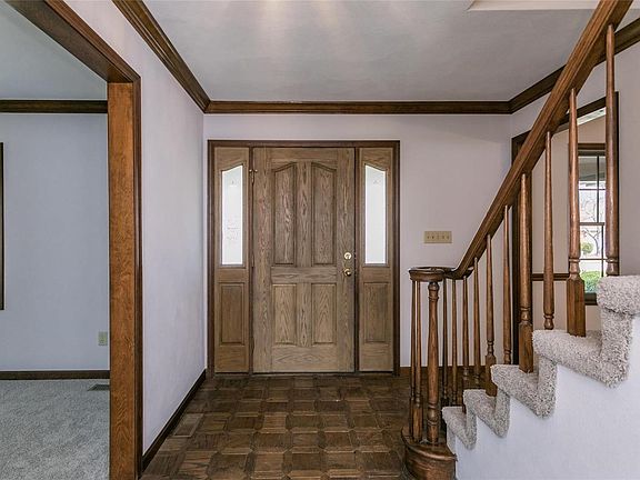 Entry foyer with spindled staircase, crown molding and wood floors.