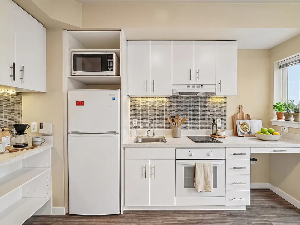 A full oven and cooktop, not just a hotplate, with counter running through to a window-side desk.