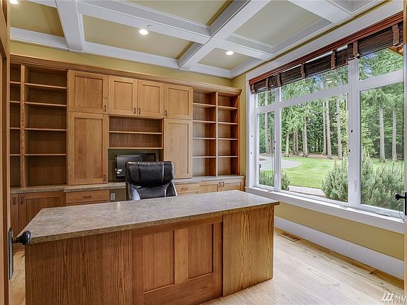 Owner's den/office with custom built-in case work and desk of 'Rift Cut White Oak'. Ceiling features a box beamed finish detail.