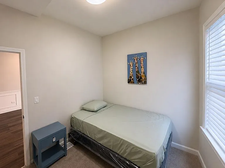 Private bedroom with carpeted flooring, a window with blinds, and space for a twin bed plus a nightstand.